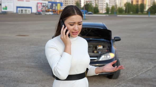 Lady in Dress Talks Against Automobile with Opened Hood