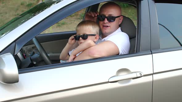 Father and Son in Sunglasses and White Tshirts in the Car