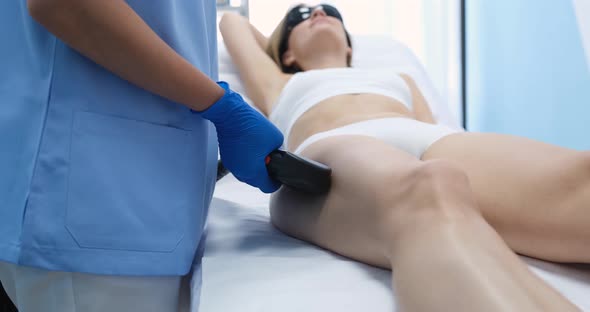 Young Woman Undergoes Procedure for Laser Hair Removal of Legs in Beauty Salon