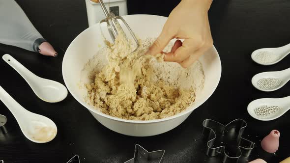 Female hand takes off pieces of raw dough from mixer blades
