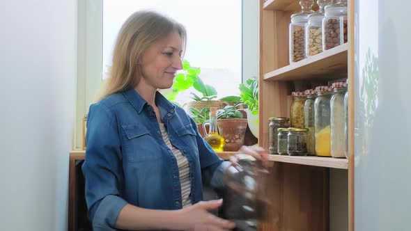 Storing Food in Pantry Middleaged Female with Oranges Can of Raisins Bottle of Olive Oil