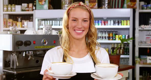 Portrait of smiling waitress offering cup of coffee