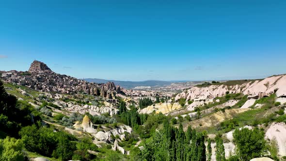 Hot air balloons fly over the mountainous landscape of Cappadocia, Turkey.