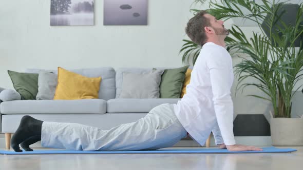 Healthy Man Doing Stretches on Yoga Mat at Home