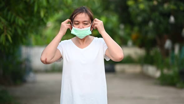 4K footage of A woman in a white T-shirt is wearing a medical mask and thumbs up.