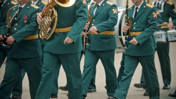 A Wind Instrument Military Parade - People in Green Costumes Walking on the Street Holding Musical