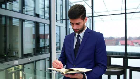 Businessman writing in diary at office