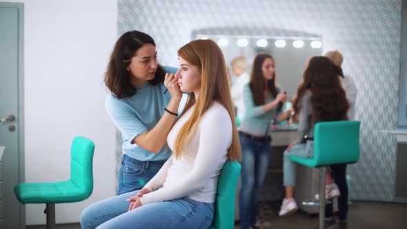 Makeup Artist Doing Makeup for Young Model at Beauty Salon