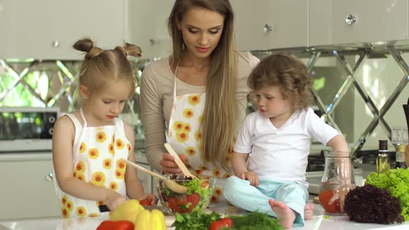 Woman With Kids Cooking Vegetables Salad At Kitchen