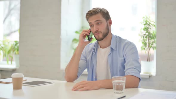 Young Creative Man Talking on Smartphone in Modern Office