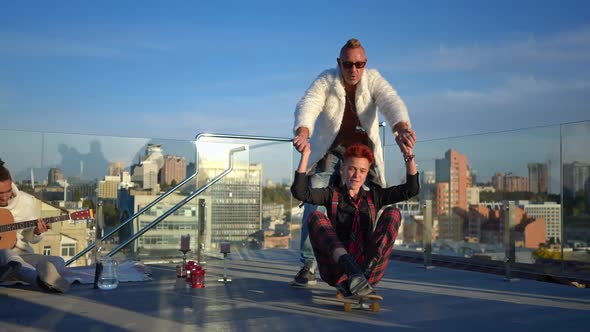 Happy Carefree Woman Sitting on Skateboard As Man Riding Girlfriend on Roof Leaving