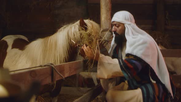 Joseph Feeding Horse in Stable