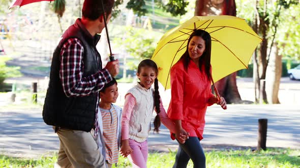 Family walking together in park with umbrella