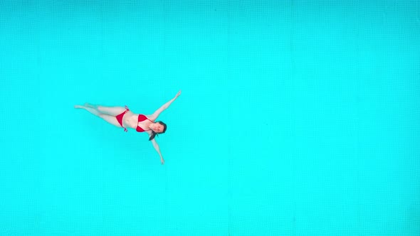 View From the Top As a Woman in a Red Swimsuit Lying on Her Back in the Pool