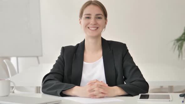 Smiling Young Businesswoman in Office Looking at Camera