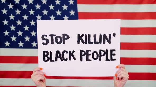Protester Holds a Banner with a Slogan - Stop Killing Black People- Against Background of the USA