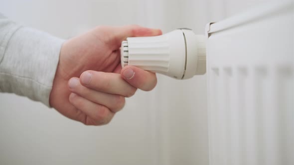 Man Hand Regulates Temperature Knob of Heating Radiator for Heating Room