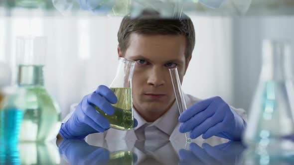 Unsure Scientist Pouring Chemical Substance Into Test Tube, Observing Reaction