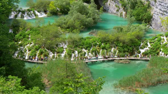 Tourists Walking the Boardwalk Over a Plitvice Lake in Plitvice Lakes National Park, Croatia. There