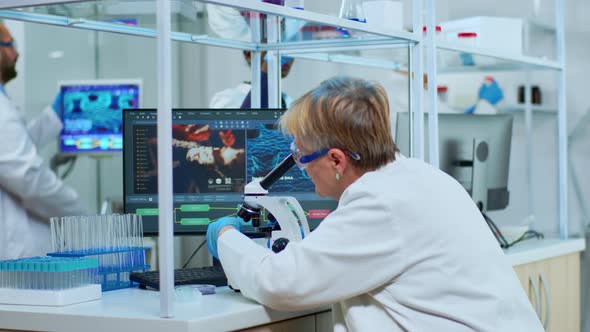 Senior Scientist Looking Through a Microscope in a Laboratory