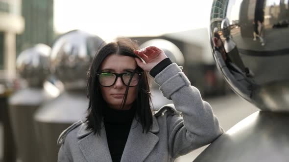 Pretty Brunette Woman is Posing in Downtown Near Modern City Sculpture