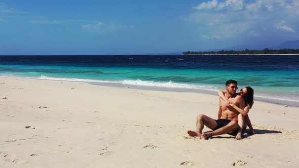 Two people tanning on exotic bay beach trip by blue green sea and white sandy background of Gili Men