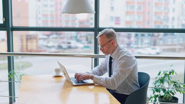 Side view of a senior man typing on a laptop