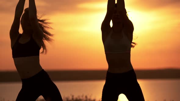 Silhouettes of Two Beautiful Girls Dancing Zumba in Field at Sunrise