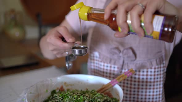 Anonymous female cook adding oil to minced meat