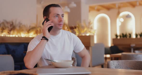 Man Talks By Phone in a Cafe