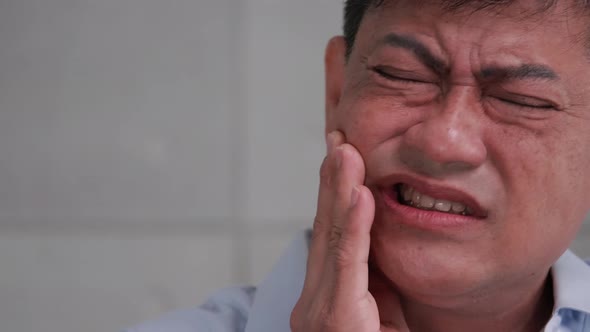 Asian senior man suffering from toothache.