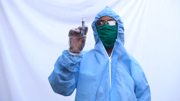 Doctor in PPE kit blue protective suit, surgical mask latex gloves. doctor holding syringe