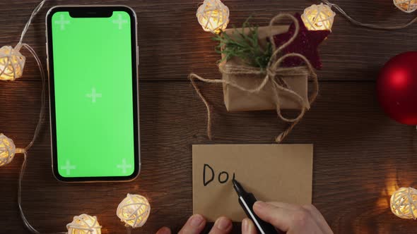 Christmas Donation Concept Hand Writing Gift Card and Green Screen Smartphone