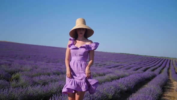 Woman in a Short Purple Dress and a Hat Stands on a Lavender Field