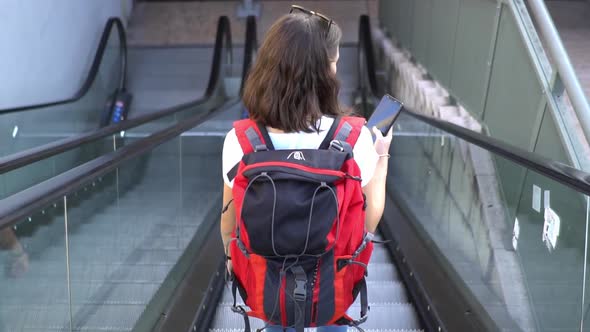 Female tourist with backpack on escalator