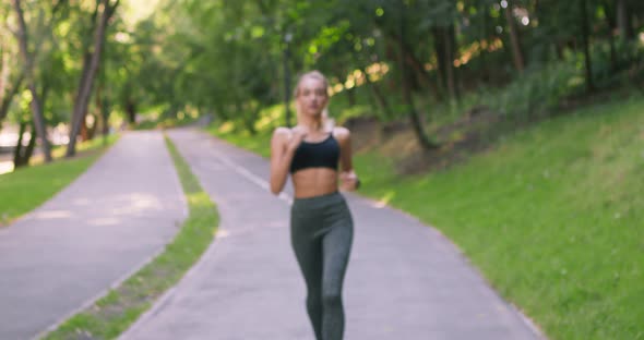 Happy Blonde Girl Running To Camera and Gesturing Thumb Up Gesture, Widely Smiling in Park