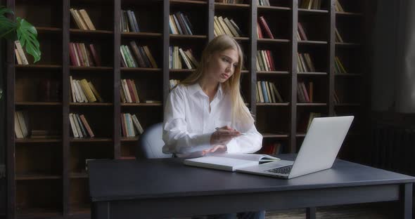 Business Woman in a White Shirt Works at a Laptop and Takes Notes