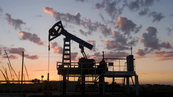 Oil Rig Stands in a Field at Sunset and Extracts Minerals