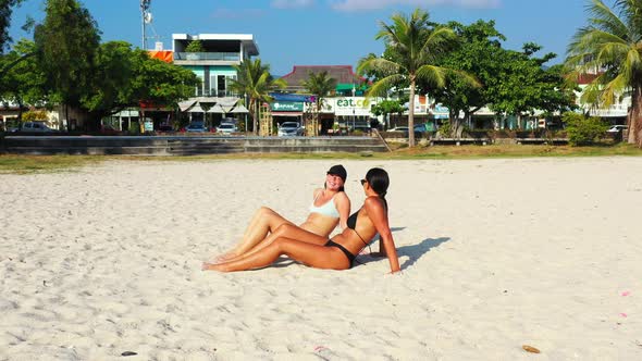 Sexy fun women travelling in the sun at the beach on summer white sandy and blue 4K background