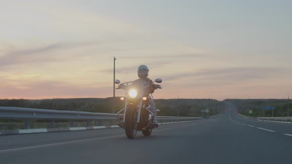 Confident serious woman rides along the highway on a cool red motorcycle in a helmet