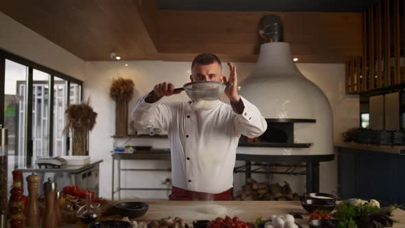 Handsome Chef Sifting Flour Using Sieve in Kitchen