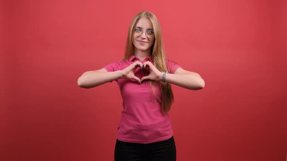 A Nice Girl Who Puts Her Hands in the Shape of a Heart and Smiles at the Camera.