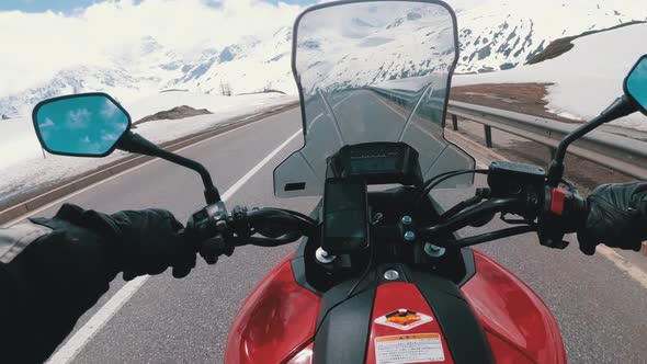 Motorcyclist Rides on Beautiful Landscape Snowy Mountain Road Near Switzerland Alps