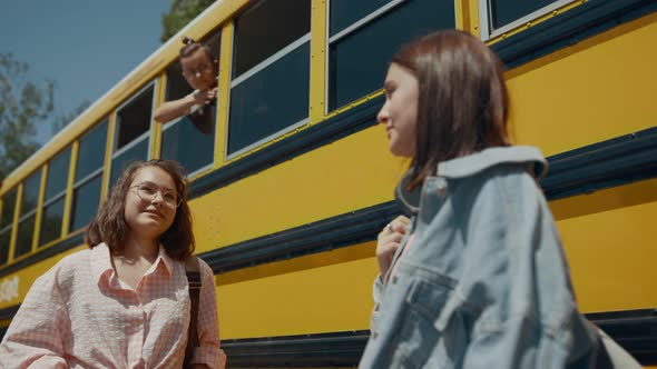 Two Cheerful Girls Talking at School Bus