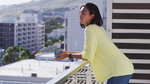 Mixed race gender fluid person drinking cup of coffee on roof terrace