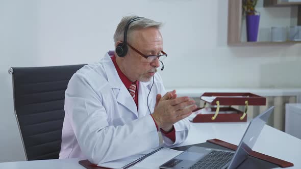 Doctor talking with patient online. Senior medic talking to client on laptop computer from his offic