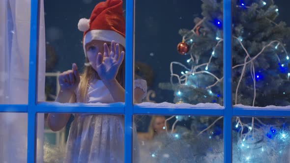 Charming Girl Through Window in Santa Hat