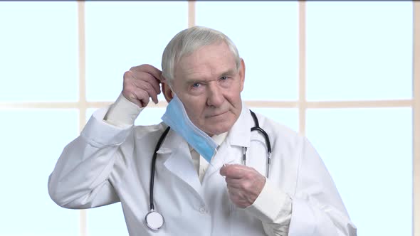 Portrait of Elder Doctor Put on Protective Blue Medical Mask.
