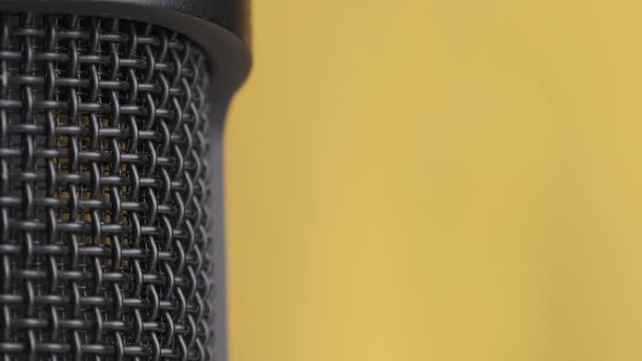 Studio Condenser Microphone Rotates on Yellow Background with Place for Text