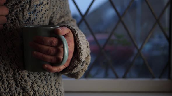 Woman with mug of hot drink in window medium shot